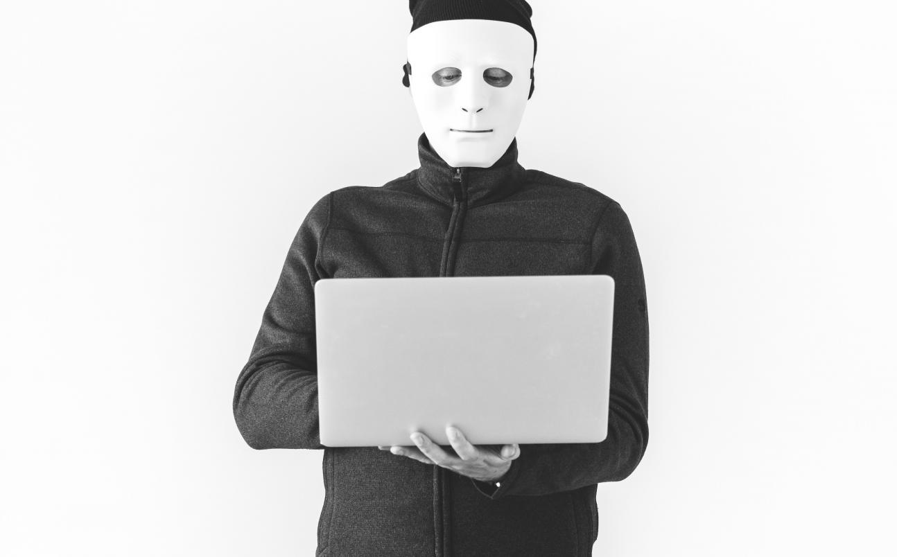 masked man using laptop