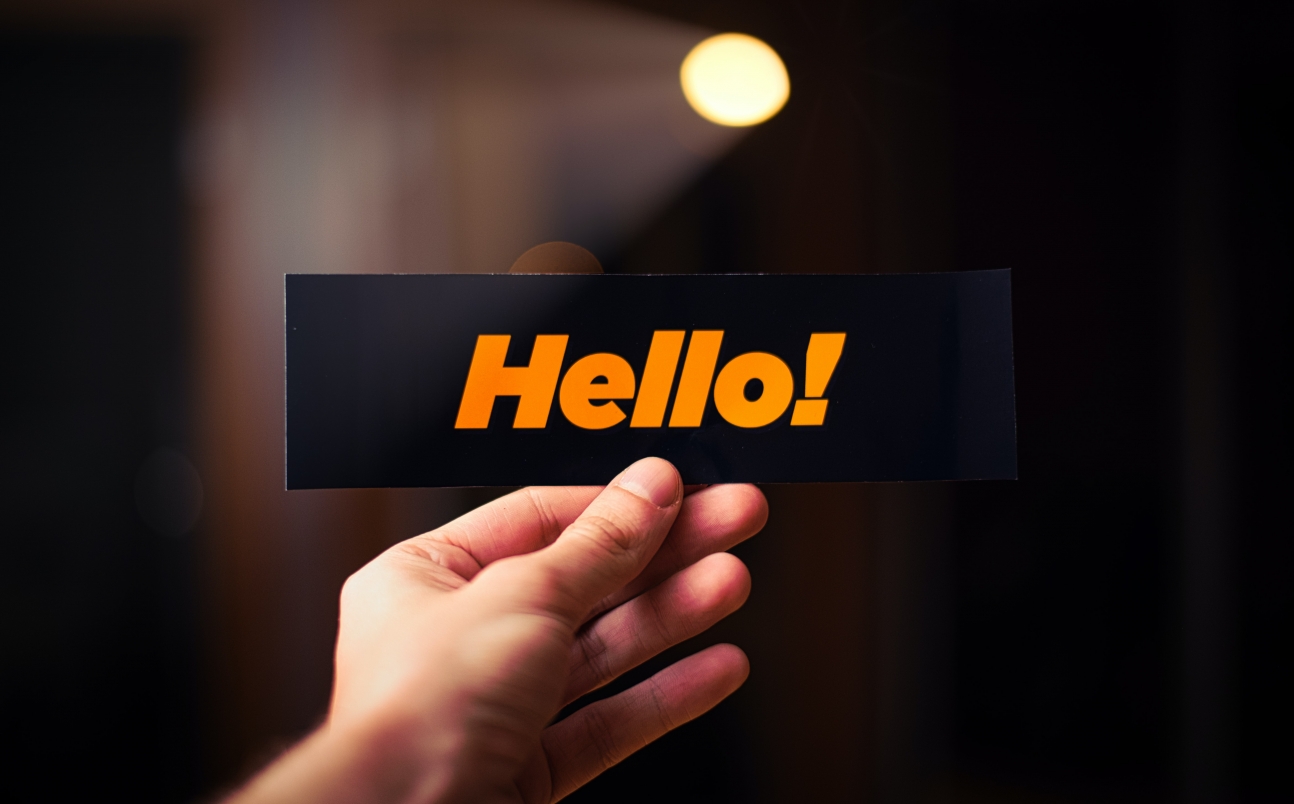 Hand holding a card with orange hello text.